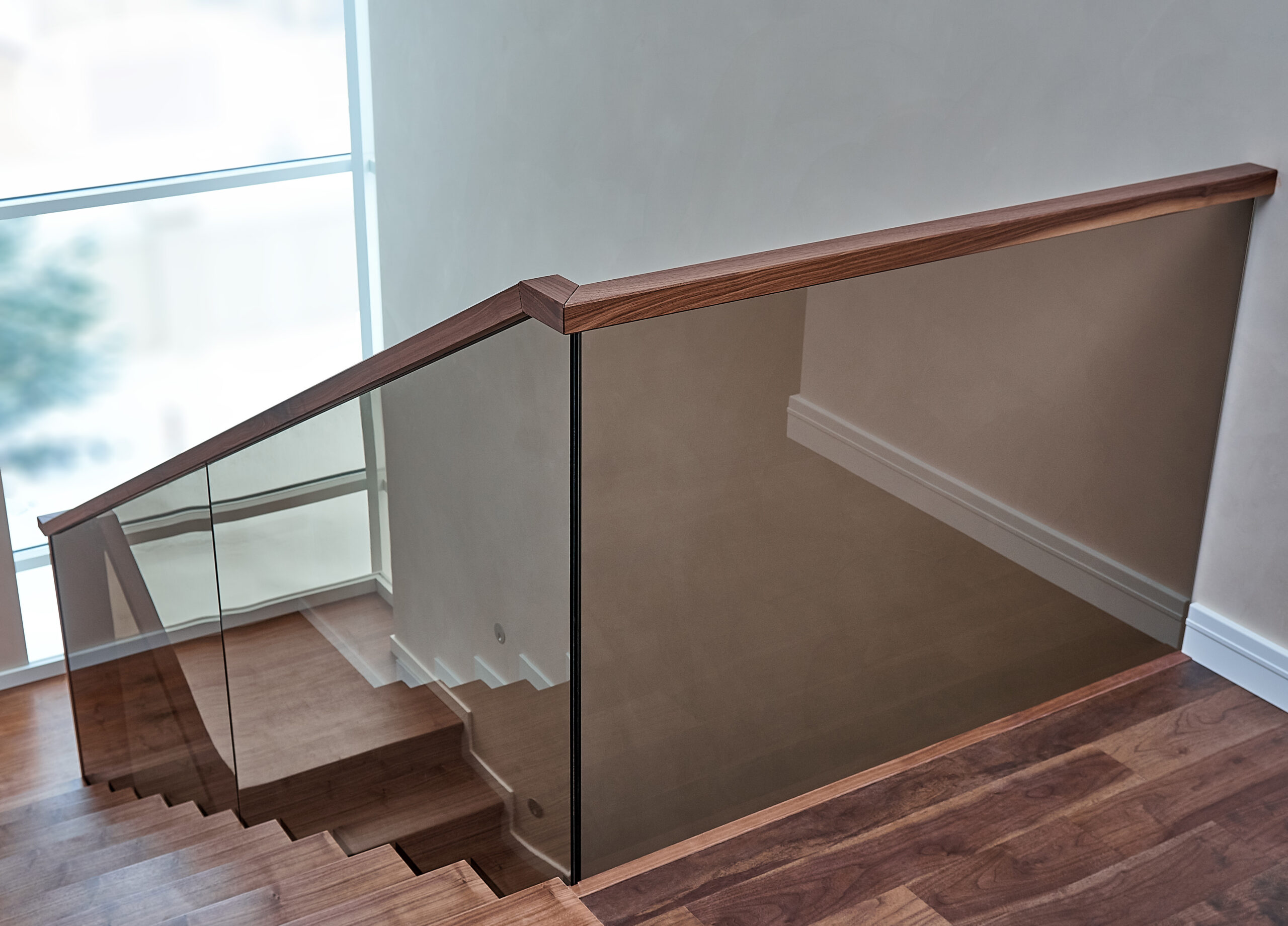 Part of wooden steps with glass railings. Walnut staircase