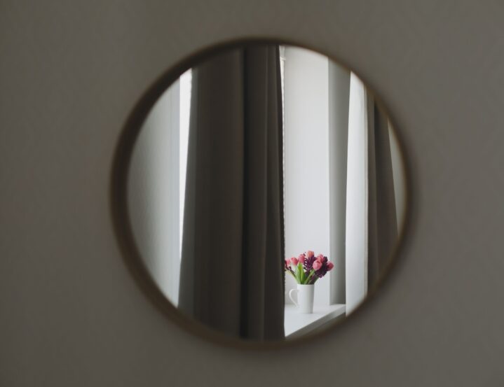 Ogledalo od stakla s pogledom na zavjese i cvijeće.