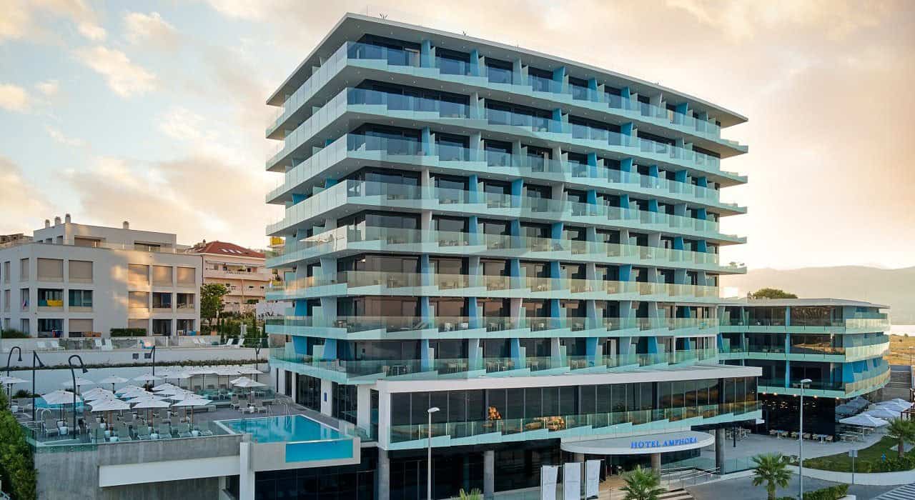 Moderni hotel s staklenim fasadama i balkonsima na obali.